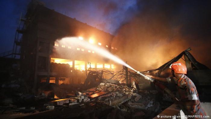 A firefighter sprays water on a building engulfed by flames