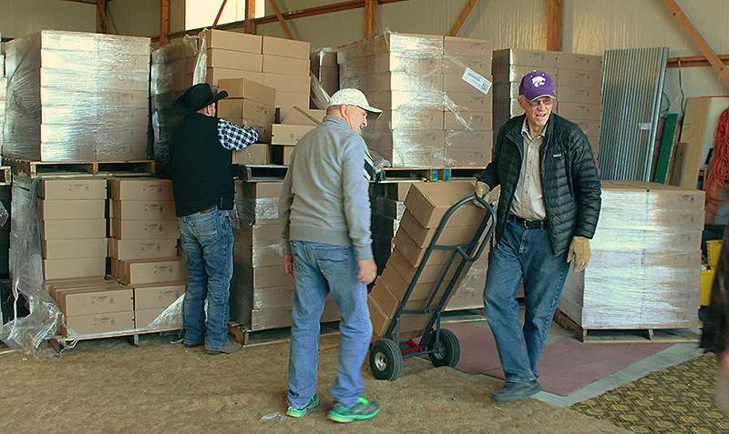 Far right, Loren Goodheart, Pantry of Blessing volunteer, and far left, Pastor Ted Stapleton, Pantry of Blessing coordinator, help load cases of Zingers out of the pantry's storage area. Photo by Cristina Janney/Hays Post