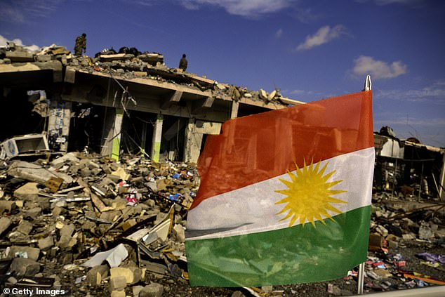 The flag of Iraqi Kurdistan flies above the ruins of the devastated town of Sinjar after its liberation in 2015. Roggio was managing a project to construct a factory and produce weapons in the Kurdistan region of Iraq in 2015 when it's alleged he tortured an employee
