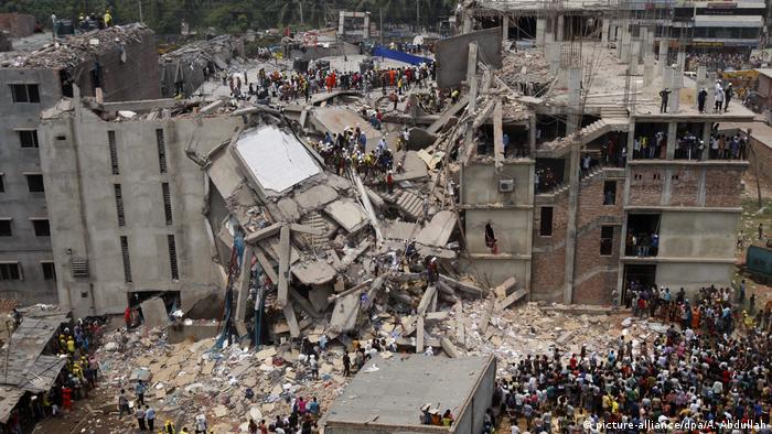 People crowd around the destroyed Rana Plaza building