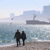 People walk on a beach in Ukrainian Black Sea city of Odessa on Monday. A cargo ship with a registered owner based in Ehime Prefecture was hit by a missile off the coast of Ukraine in the Black Sea on Friday, causing a fire on board. | AFP-JIJI