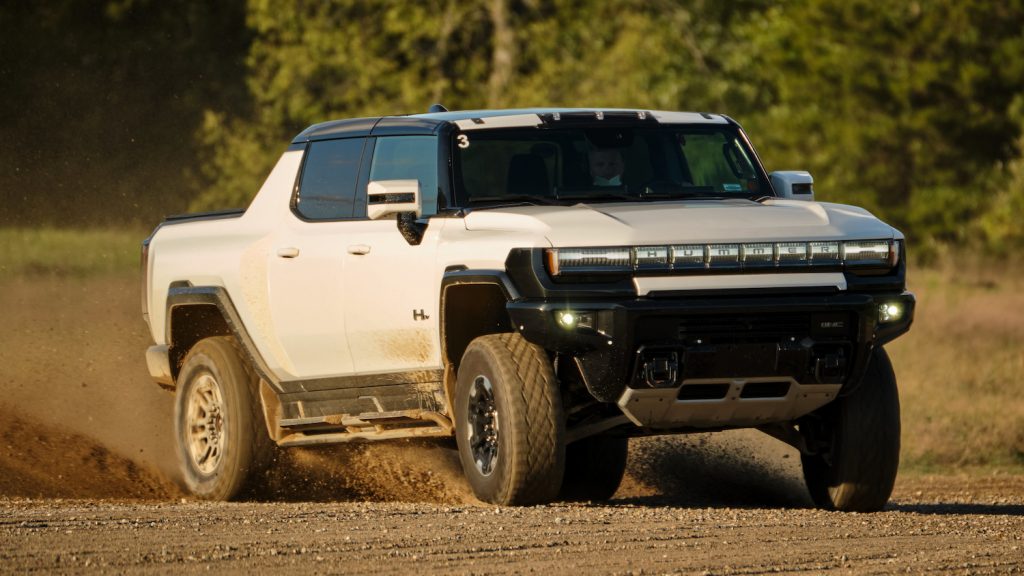 White GMC Hummer EV supertruck off-roading at the General Motors' testing ground.