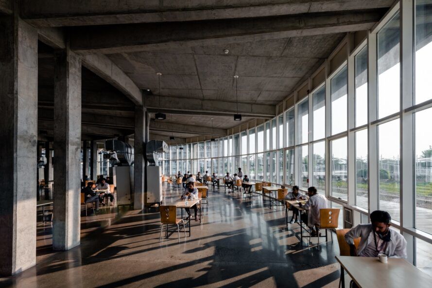 An indoor sitting area with tables and chairs lining against the wall of windows
