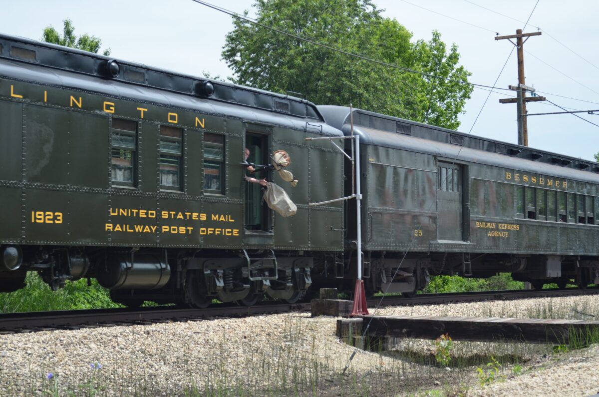 A postal clerk catches mail while also throwing a pouch from the train. (Photo: Illinois Railway Museum)
