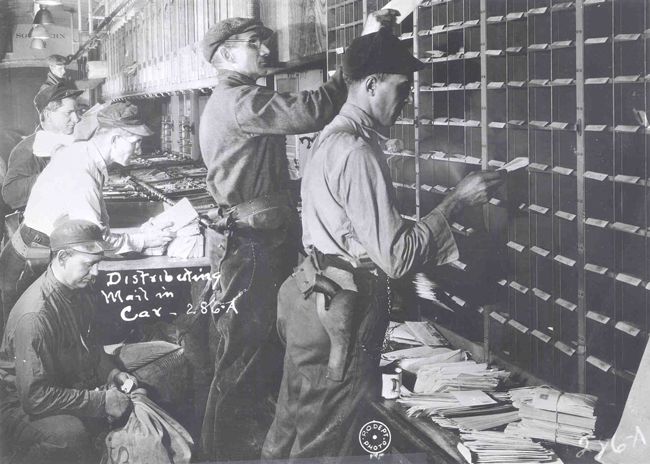 From the 1870s to the 1950s, railroads were the primary mode of mail transportation in the U.S. To speed delivery, clerks rode in the cars, sorting mail en route. In 1921, due to a rash of train robberies following World War I, Postmaster General Will H. Hays armed railway mail clerks, ordering them to shoot to kill to protect the mail. In 1921 and again in 1926, U.S. Marines were also assigned to guard mail trains. (Photo: USPS Collection)