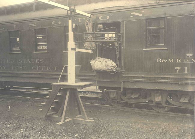 A side view of RPO #71 on the Burlington and Missouri River Railroad in Nebraska, with its catcher arm grabbing a pouch of mail from a crane and a mail pouch for local delivery being tossed out. Exchanging mail at small towns without stopping speeded delivery to those communities without disrupting mail schedules between major terminals. (Photo: USPS Collection)