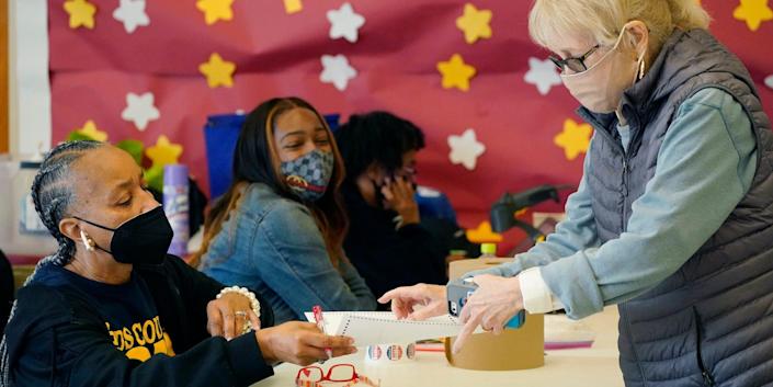 Amy Barnes, left, the Initializing Manager, hands a ballot, an "I Voted in Hinds County" sticker and special pen to a voter in a north Jackson, Miss., precinct, Tuesday, Nov. 2, 2021.