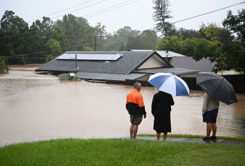 Residents of Goodna, Queensland, watch on as flood waters submerge a home.