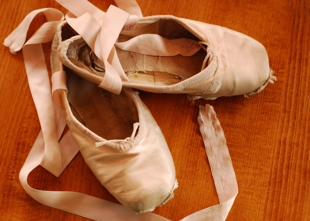 Worn out pointe shoes on a wooden dance floor