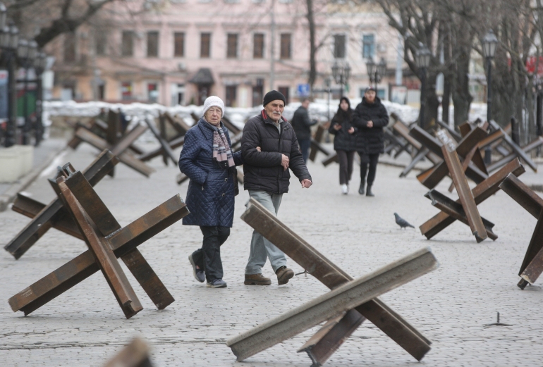 Locals walk on a street between anti-tank Czech hedgehogs set up in the south Ukrainian city of Odesa in preparation for a Russian advance