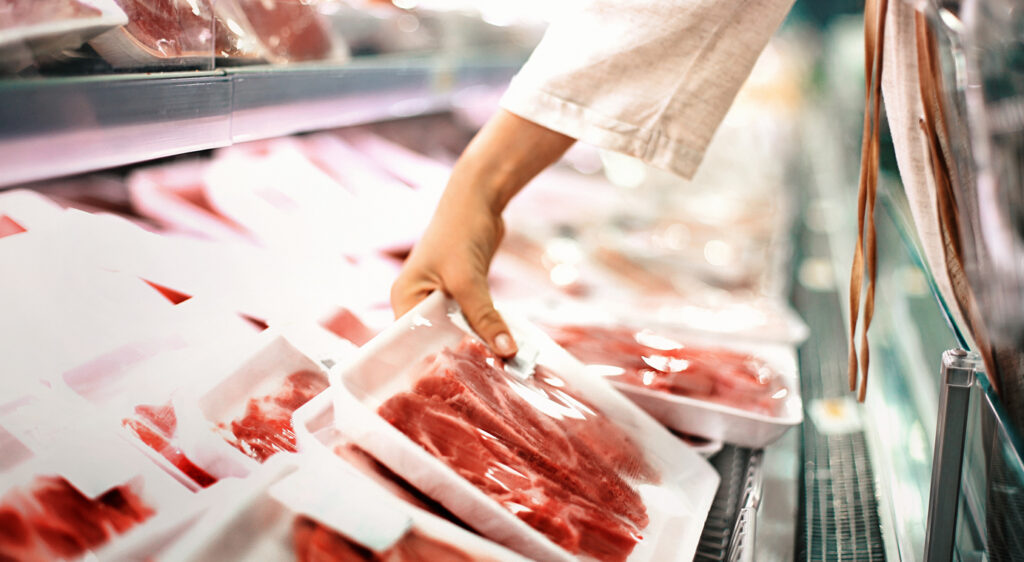 Female consumer buying organic meat products sold in a grocery store.