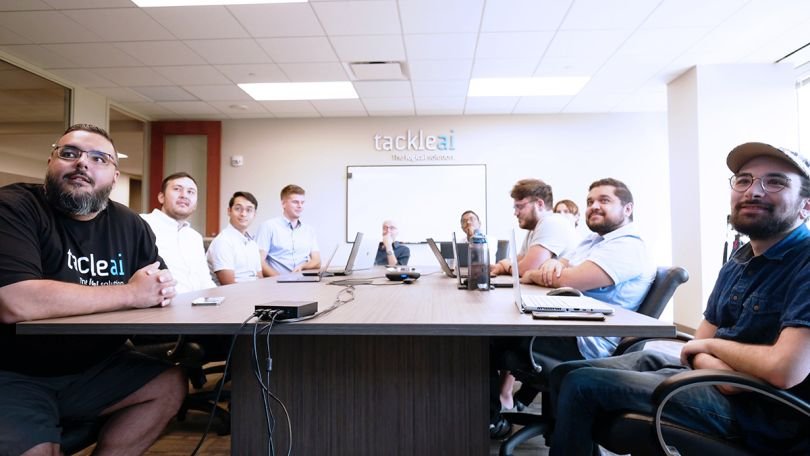 Tackle.AI team members having a meeting sitting around a conference table 
