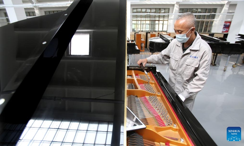 A tuner tunes a piano at Dongbei Piano Musical Instruments Co., Ltd. in Yingkou, northeast China's Liaoning Province, April 25, 2022. Dongbei Piano Musical Instruments Co., Ltd., formerly known as Dongbei Piano Factory in Yingkou, is gradually resuming production with epidemic prevention measures in place.(Photo: Xinhua)