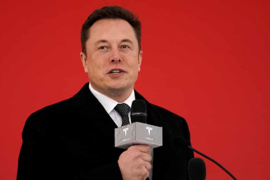 Elon Musk holds a microphone with a Tesla logo on it.