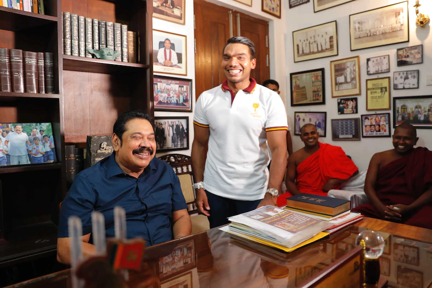 Sri Lankan Prime Minister Mahinda Rajapaksa sits for photographs, with his lawmaker son Namal by his side.
