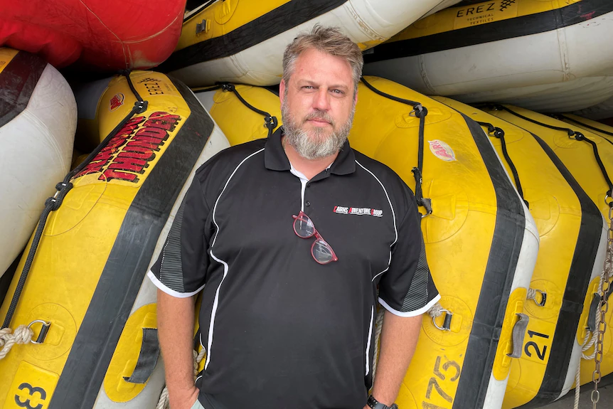 A man stands in front of rafting boats