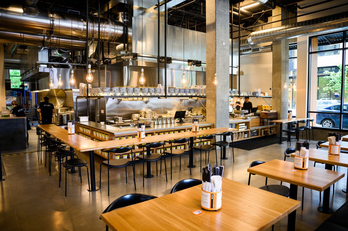 White pine tables and bars line up around an open format kitchen at Afuri.