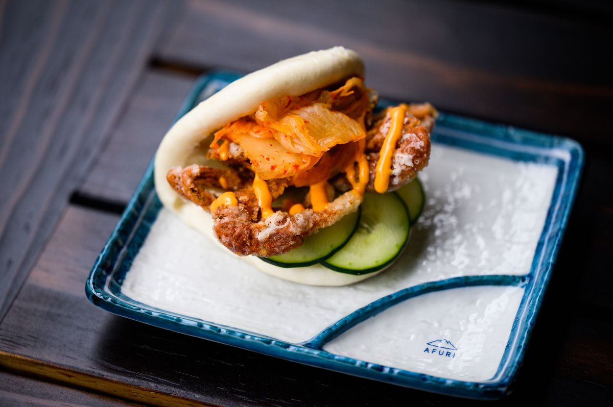 A fried soft-shell crab comes with kimchi in a small bao bun, served on an Afuri-branded plate.