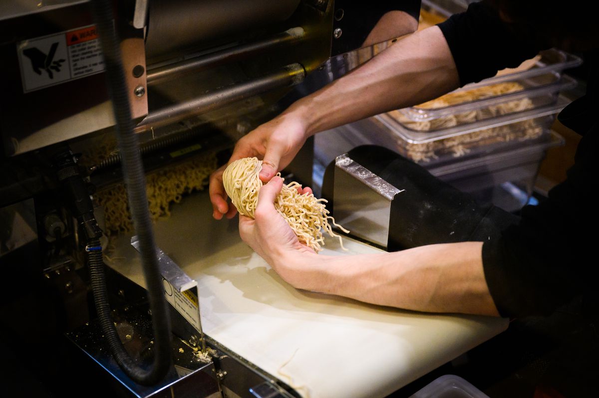 Two hands grab a bundle of noodles at Afuri, next to a tray of other bundles.