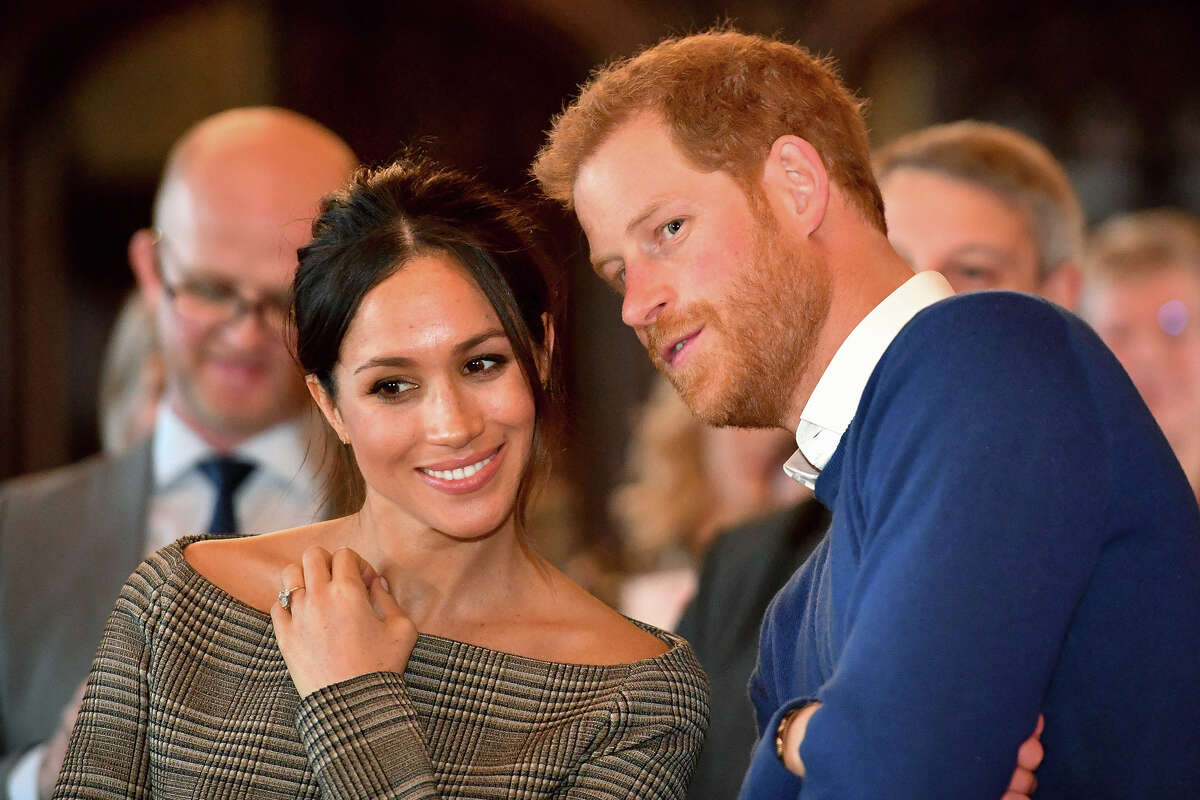 Prince Harry whispers to Meghan Markle as they watch a dance performance by Jukebox Collective in the banqueting hall during a visit to Cardiff Castle on January 18, 2018 in Cardiff, Wales, The couple keep their primary home and are raising their two children in Montecito, a place that is both home to the world's wealthiest and most famous and rife with danger from climate change.
