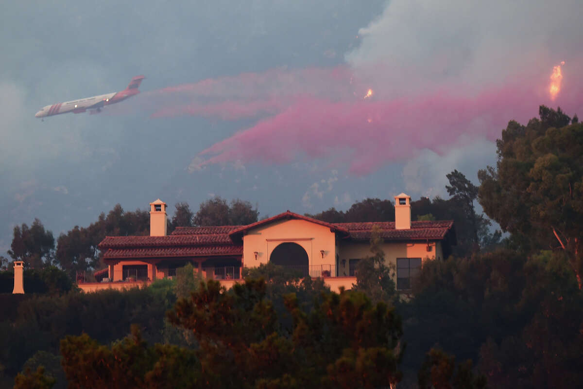 A plane drops flame retardant on a luxury home threatened by the Thomas Fire, on a hillside in Santa Barbara, Calif., on Dec. 11, 2017.