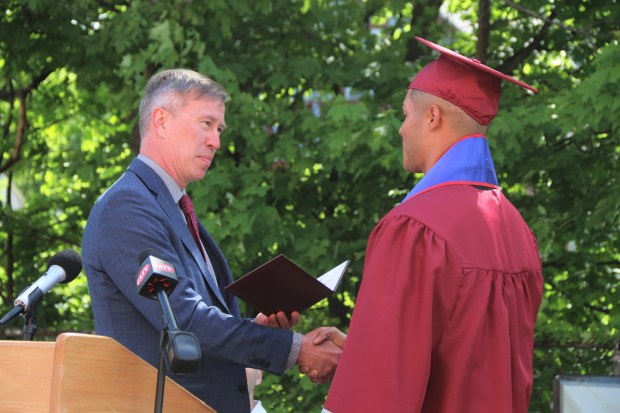 Fitchburg Public Schools Superintendent Robert Jokela (l.) presents Goodrich Academy senior Mathews Cardeal with his high school diploma during a special graduation ceremony held for the 21-year-old on May 23. (DANIELLE RAY/SENTINEL & ENTERPRISE)