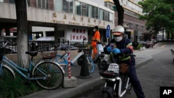 Workers stand near an entrance to the Wanliu Campus of Peking University on May 17, 2022 in Beijing.