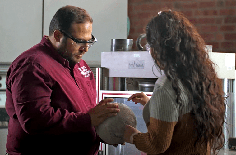Mohammed Albattiti and a student examine a sphere of concrete.