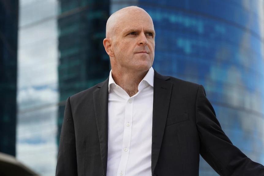 Man wearing a suit with a building in the background.