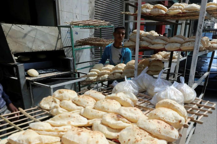 A baker arranges bread at a bakery