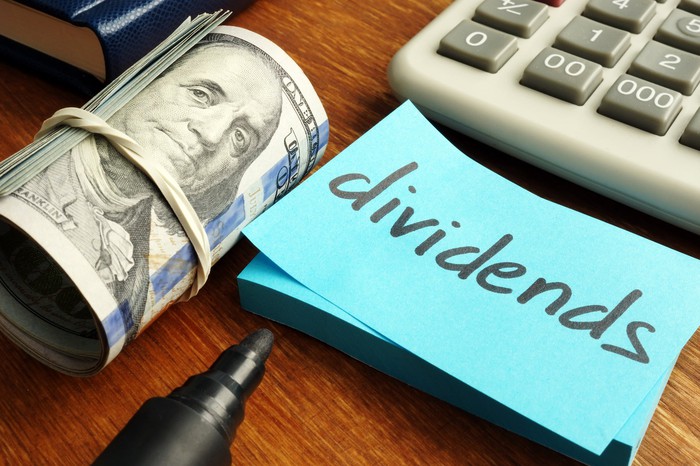 Calculator, roll of money, and a note that says dividends. 