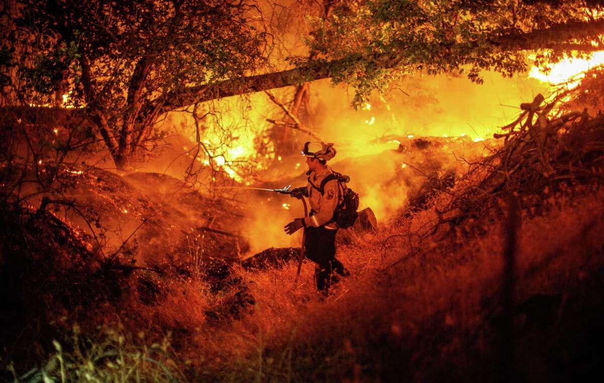 A firefighter douses flames from the Electra Fire in Mokelumne Hill, in Calaveras County, Calif., on Monday, July 4 2022.