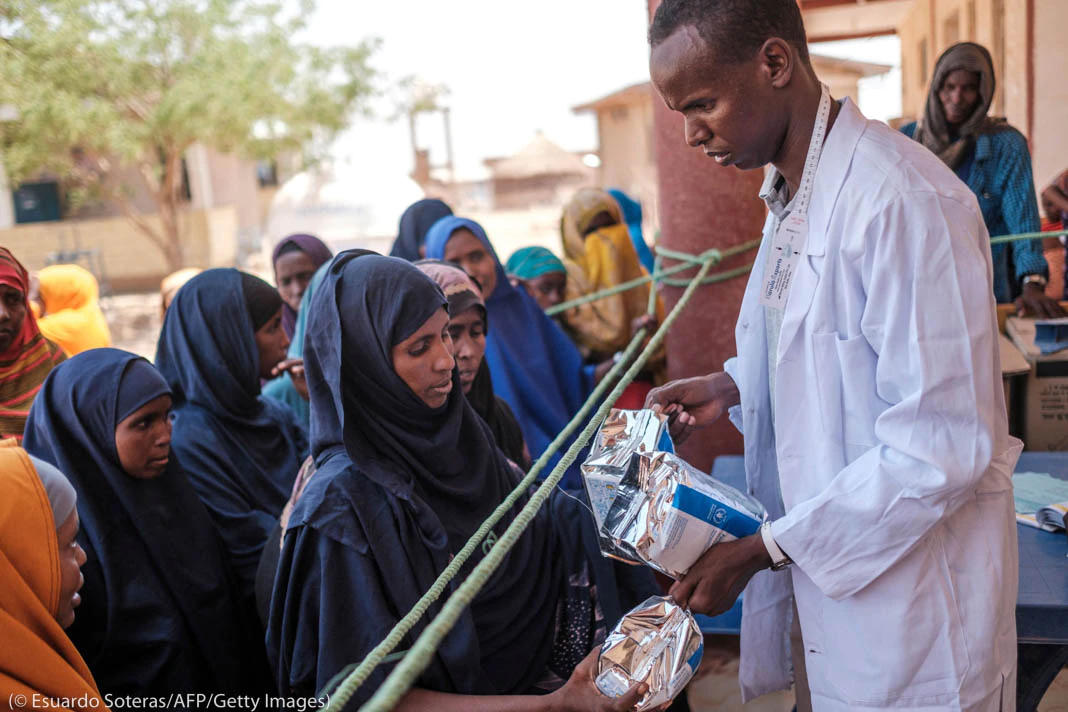 Man handing packets of food to group of people (© Eduardo Soteras/AFP/Getty Images) Man handing packets of food to group of people (© Eduardo Soteras/AFP/Getty Images)