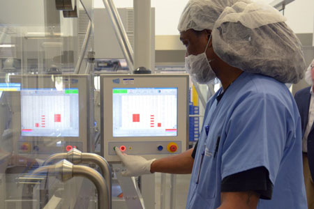 Man wearing scrubs pressing button on machine