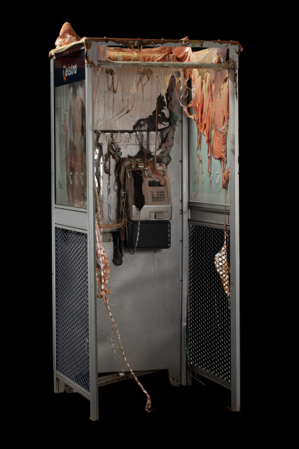 a melted phone booth is photographed with a black background