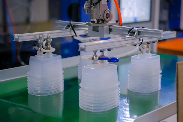 Food containers on conveyer belt with plastic injection molding machine
