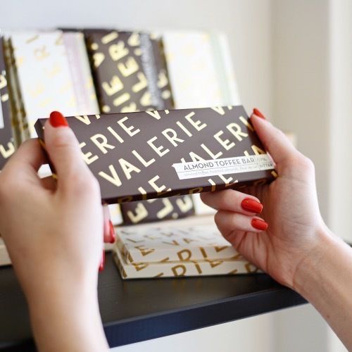 Hands picking up a Valerie Confections chocolate bar.