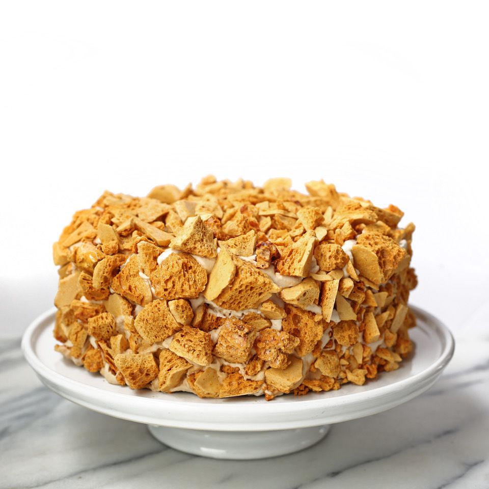 A white frosted cake with crunchy bits of coffee cake on top.