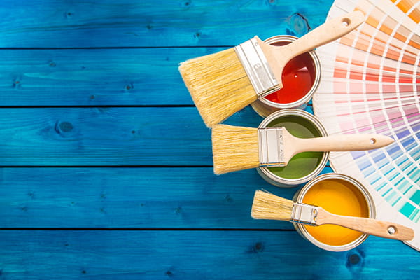 A paint palette, various paint cans, brushes and wooden panels painted blue as a symbolic image.