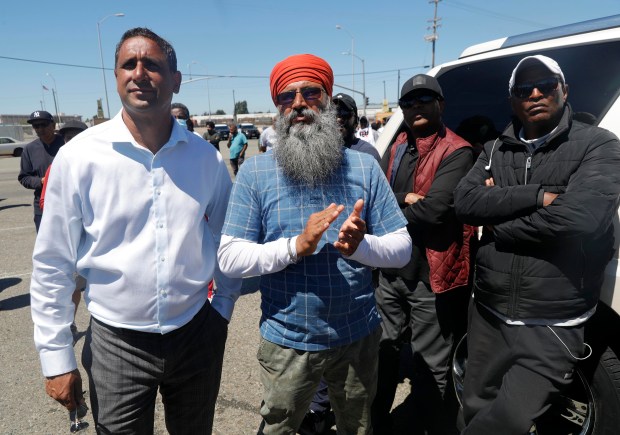 OAKLAND, CALIFORNIA - JULY 21: Spokesperson Navdeep Gill and truck driver Kulginder Singh, from left, take part in a truckers rally during a protest in front of Matson shipping at the Port of Oakland in Oakland, Calif., on Thursday, July 21, 2022. Truck drivers have blocked access to container terminals in protest of state Assembly Bill 5, a bill that creates standards for classifying workers as independent contractors. (Jane Tyska/Bay Area News Group)
