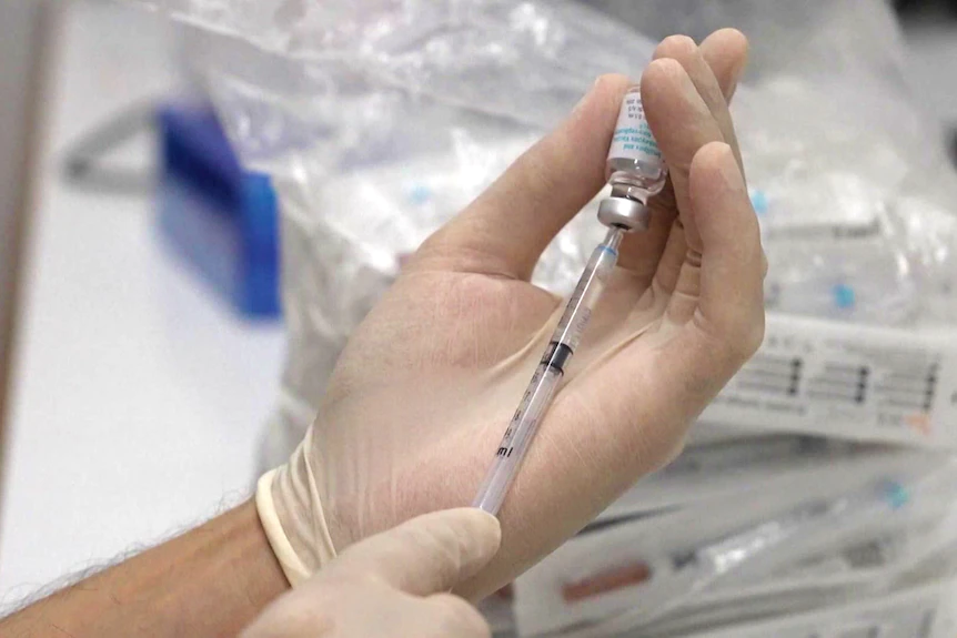 a person holding a vial of vaccine and injection