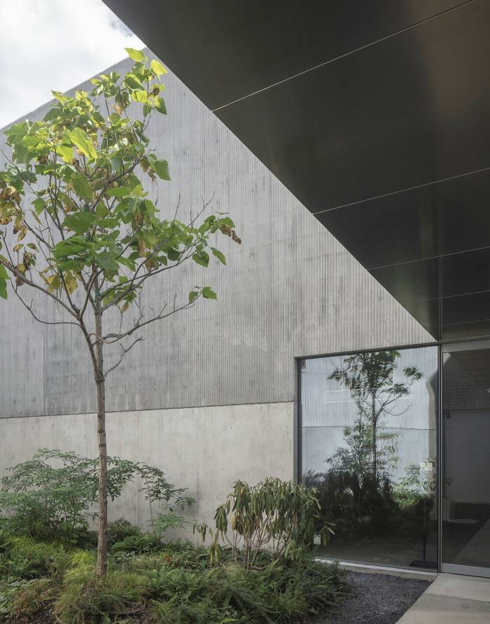 A sliding door leads to a covered pathway by a garden