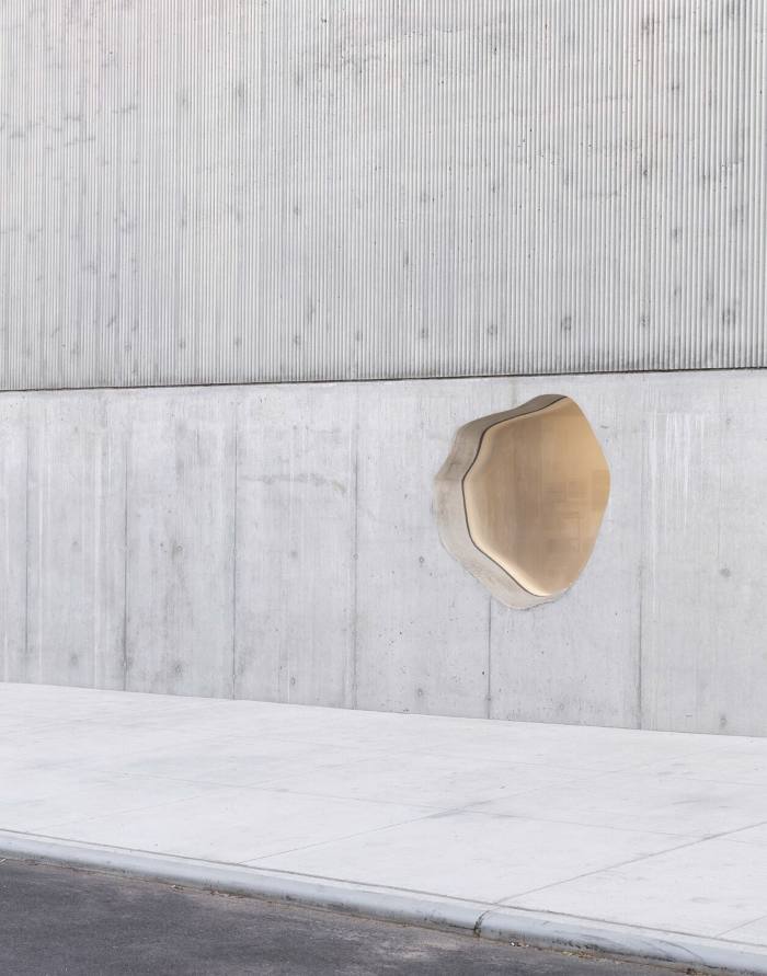 A roughly circular window in a light grey concrete wall