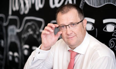 Vic Goddard, in a shirt and tie, half-smiles as he raises his glasses