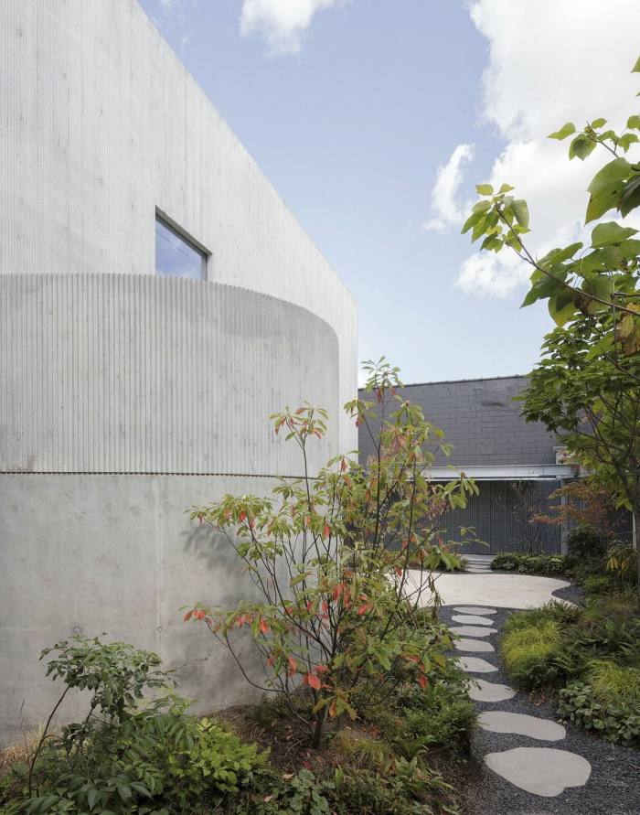 Circular paving leads through a garden between buildings