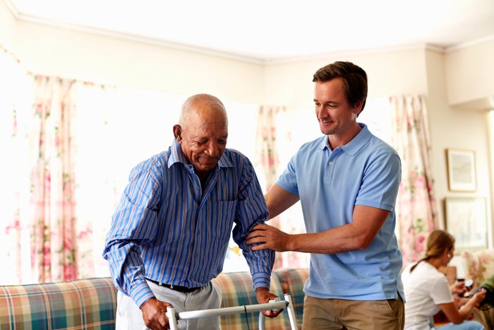 A person helping another person with a walker.