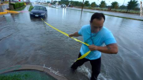 Mon Lun pulls a strap to his water stalled car Monday before towing it out of receding flood waters in Dallas.