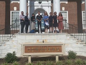 Six students stand on front steps of Delaware Department of Education building, smiling at the camera.