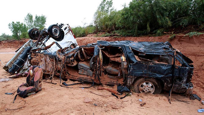 The twisted wreckage of two vans that were washed away in a flash flood with women and children inside rest on the bank of Short Creek on September 15, 2015 in Hildale, Utah.