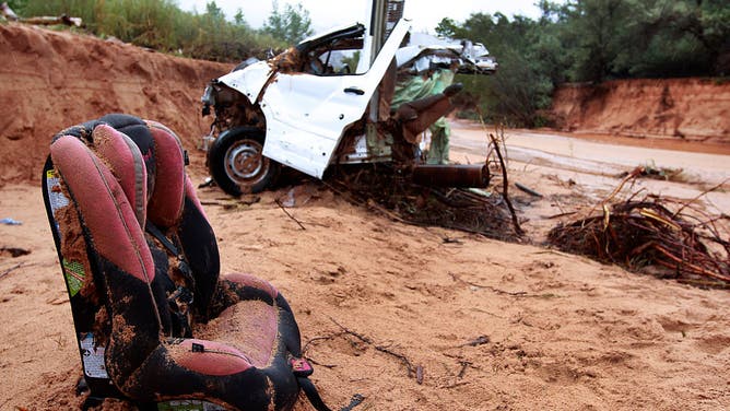 A baby seat sits in front of half of one of two vans that were washed away in a flash flood with women and children inside rest on the bank of Short Creek on September 15, 2015 in Hildale, Utah.